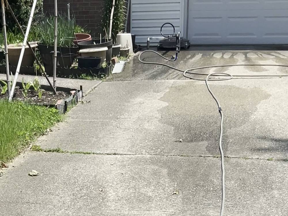 Before: grey, stained concrete driveway in front of a white garage